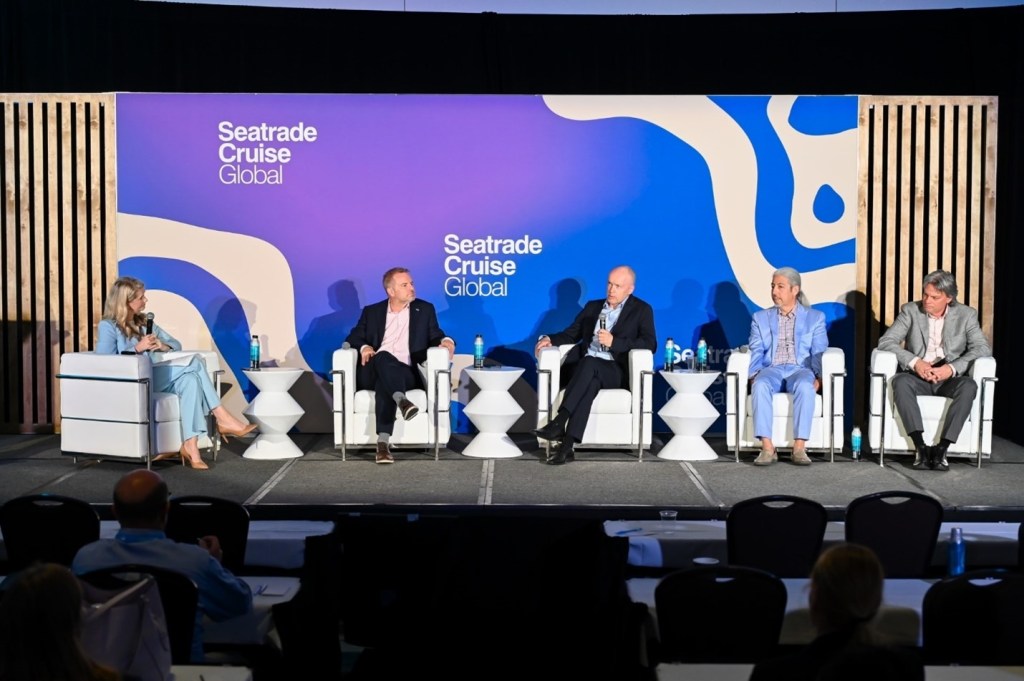 5 panelists in white arm charges on a stage in front of a Seatrade Cruise Global backdrop