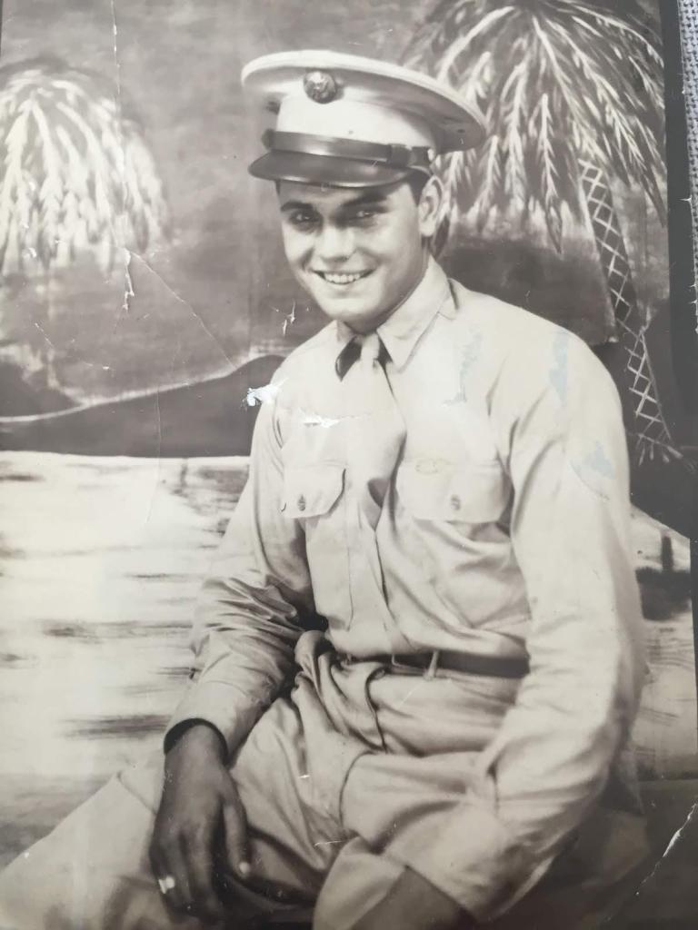 Man sitting and smiling into the camera in a U.S. military uniform.